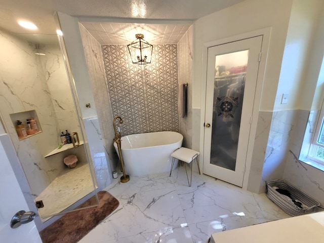 bathroom featuring a chandelier and separate shower and tub