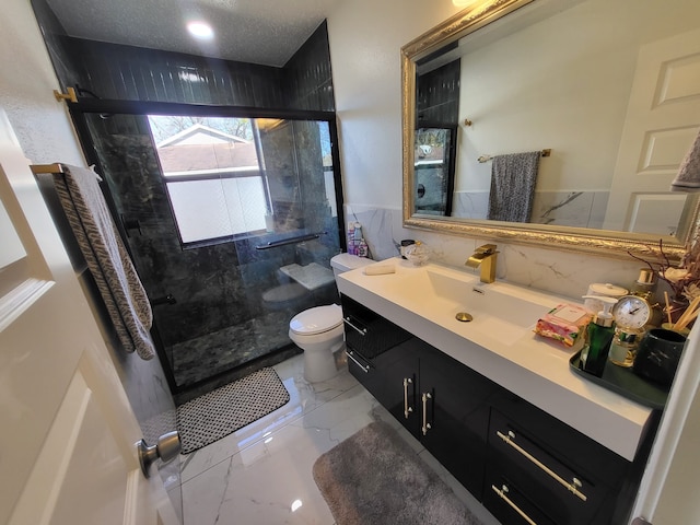 bathroom with a textured ceiling, vanity, toilet, and a shower with shower door