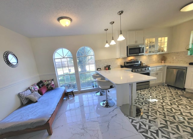 kitchen featuring white cabinets, a breakfast bar, hanging light fixtures, and appliances with stainless steel finishes