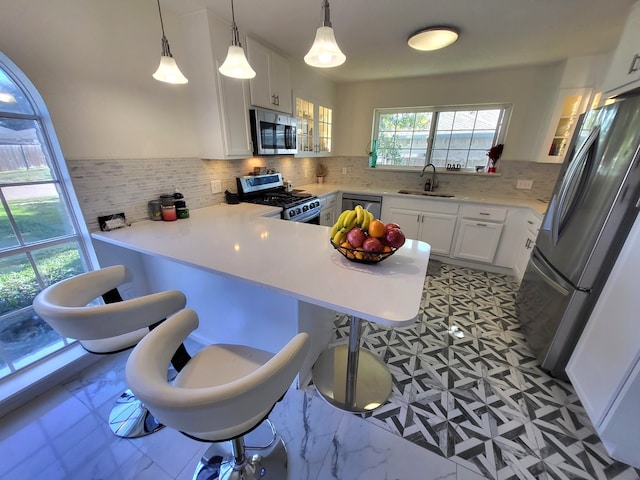 kitchen featuring kitchen peninsula, appliances with stainless steel finishes, a kitchen breakfast bar, sink, and white cabinetry