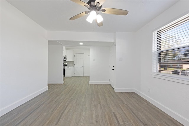 empty room with ceiling fan and light hardwood / wood-style flooring