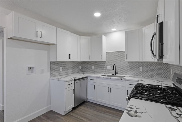 kitchen with white cabinets, light stone countertops, backsplash, and appliances with stainless steel finishes