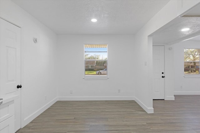 empty room with plenty of natural light, wood-type flooring, and a textured ceiling