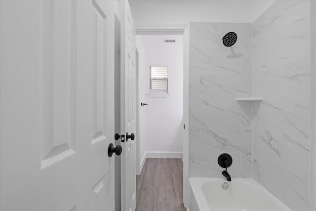 bathroom with wood-type flooring and tiled shower / bath