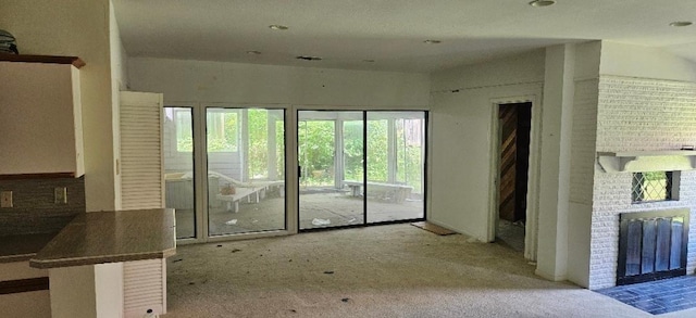 unfurnished living room featuring a fireplace, light colored carpet, and plenty of natural light