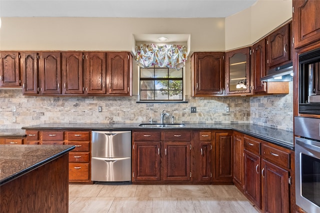 kitchen with sink, stainless steel appliances, tasteful backsplash, dark stone counters, and light tile patterned floors