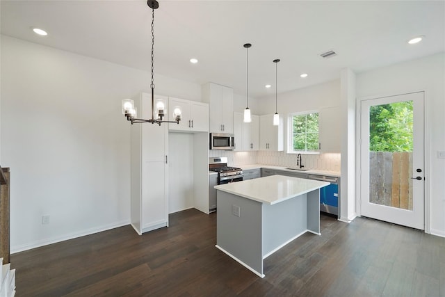 kitchen with dark hardwood / wood-style flooring, a kitchen island, sink, white cabinetry, and hanging light fixtures