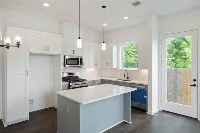 kitchen featuring a center island, stainless steel appliances, white cabinetry, and sink