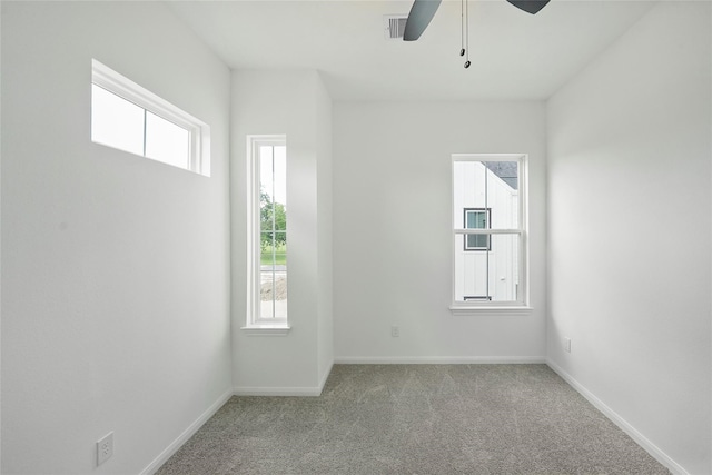 empty room featuring light carpet, a wealth of natural light, and ceiling fan