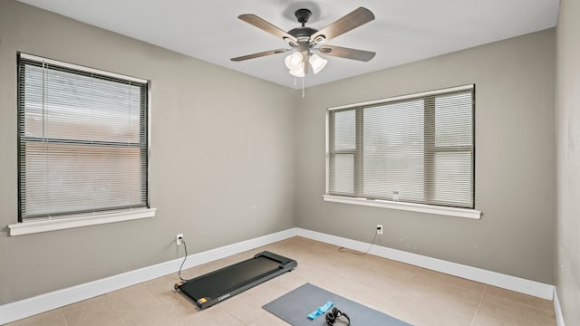 exercise area with ceiling fan and light tile patterned floors