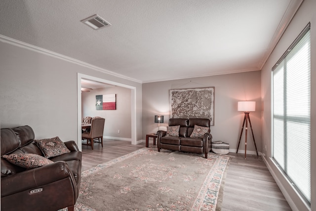 living room featuring a textured ceiling, light hardwood / wood-style floors, and crown molding