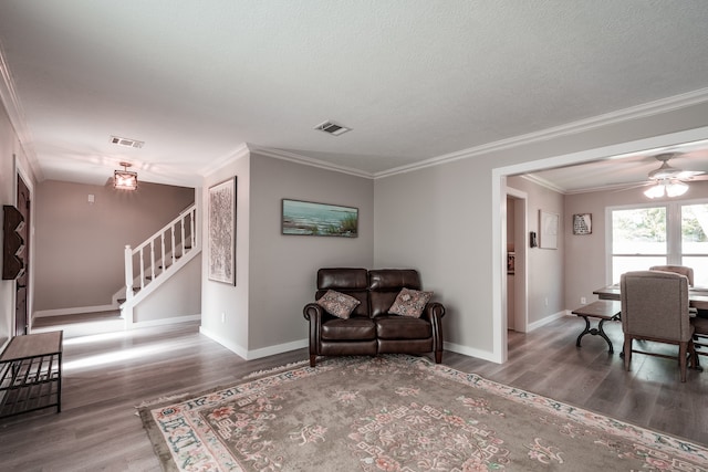 living room with ceiling fan, wood-type flooring, a textured ceiling, and ornamental molding