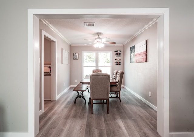 dining area featuring ceiling fan, crown molding, wood-type flooring, and a textured ceiling