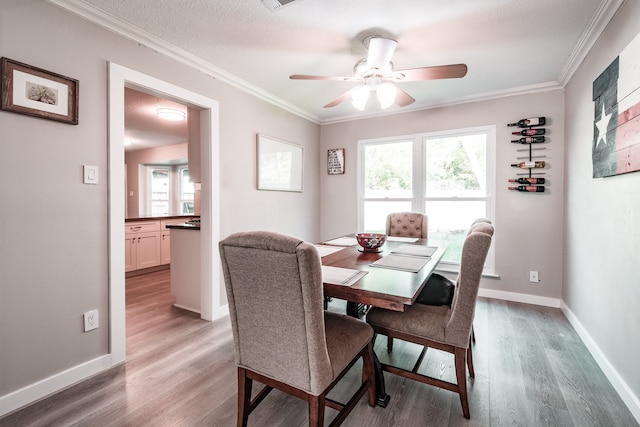 dining area featuring a textured ceiling, hardwood / wood-style flooring, ceiling fan, and crown molding