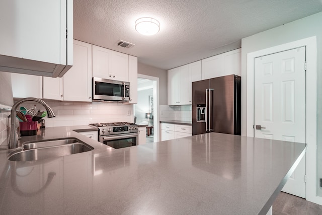 kitchen with white cabinets, high quality appliances, sink, and a textured ceiling