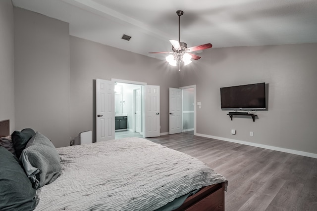 bedroom featuring hardwood / wood-style floors, ceiling fan, ensuite bathroom, and vaulted ceiling