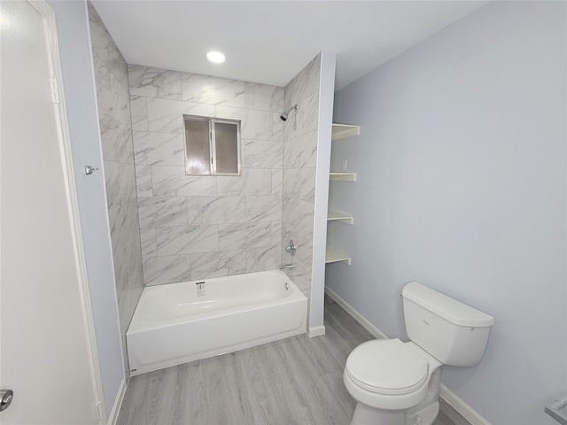 bathroom with toilet, tiled shower / bath, and hardwood / wood-style flooring