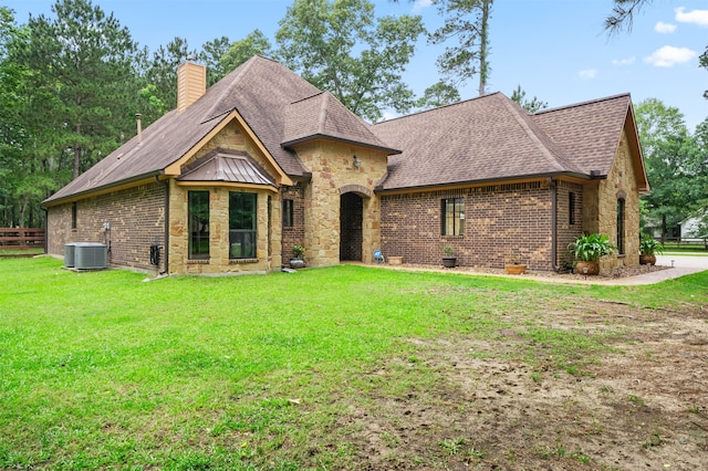 view of front of house with central AC unit and a front lawn