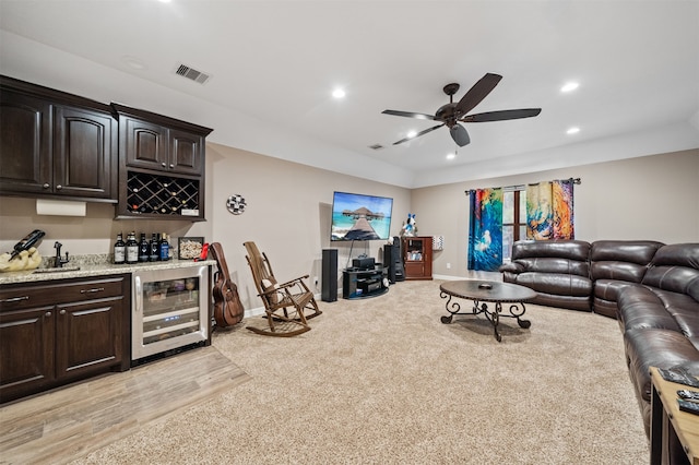 living room with light wood-type flooring, wet bar, beverage cooler, and ceiling fan