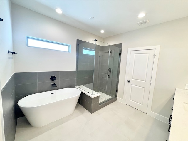 bathroom featuring tile patterned flooring, vanity, separate shower and tub, and tile walls