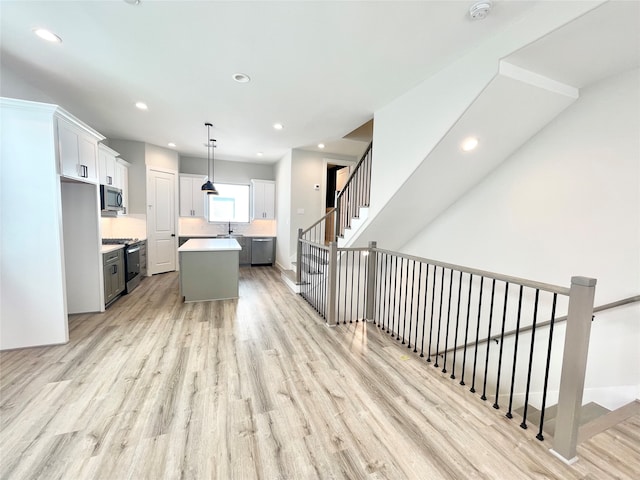 kitchen with gray cabinetry, stainless steel appliances, light hardwood / wood-style flooring, pendant lighting, and a kitchen island