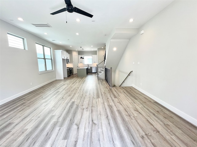 unfurnished living room with light wood-type flooring and ceiling fan