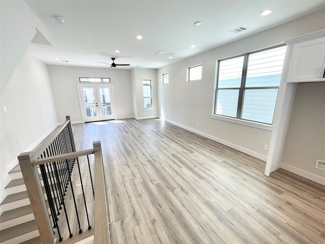 unfurnished living room featuring ceiling fan, light hardwood / wood-style flooring, a healthy amount of sunlight, and french doors