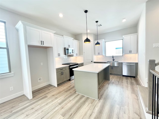 kitchen featuring white cabinets, appliances with stainless steel finishes, a kitchen island, and pendant lighting