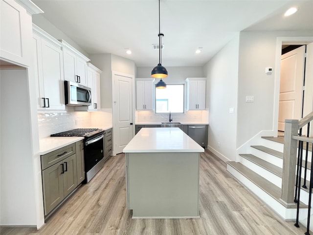 kitchen featuring white cabinetry, light hardwood / wood-style flooring, a kitchen island, and stainless steel appliances