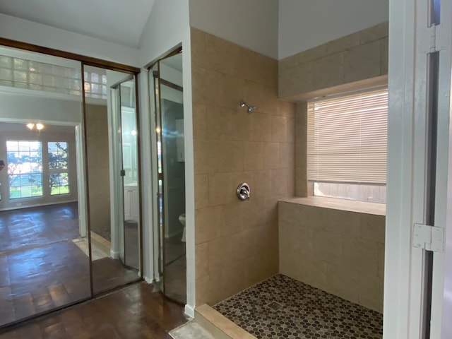 bathroom featuring a tile shower, toilet, and lofted ceiling