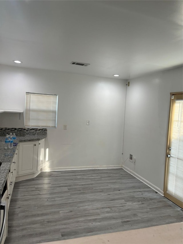 interior space featuring white cabinets, light wood-type flooring, and dark stone countertops