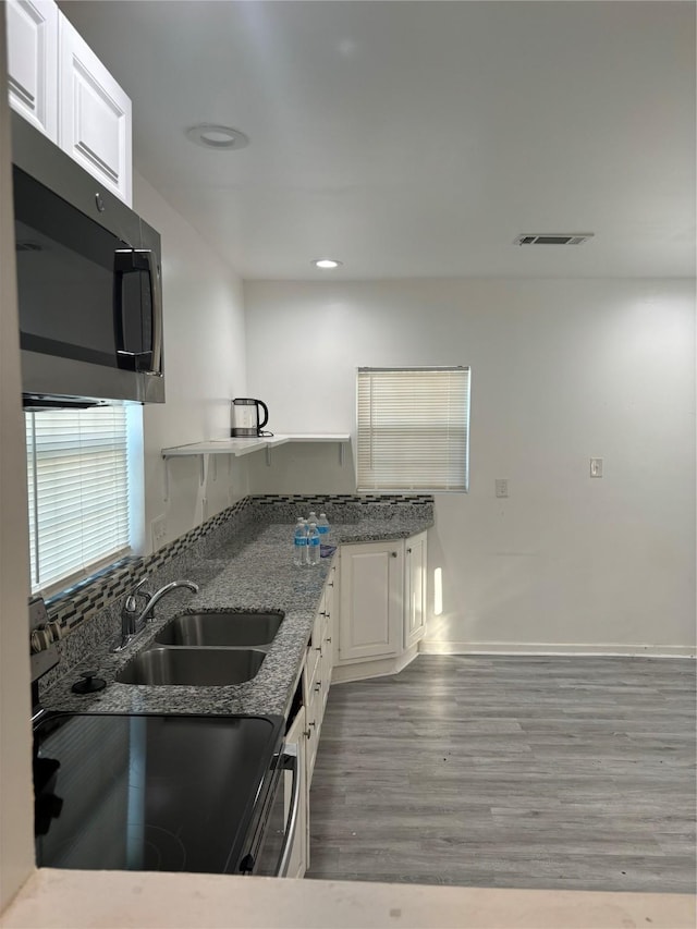 kitchen featuring hardwood / wood-style floors, sink, light stone countertops, appliances with stainless steel finishes, and white cabinetry