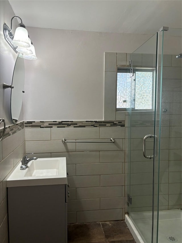 bathroom featuring a shower with door, vanity, and tile walls