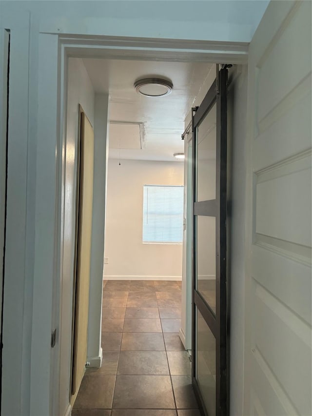 hallway with dark tile patterned flooring and a barn door