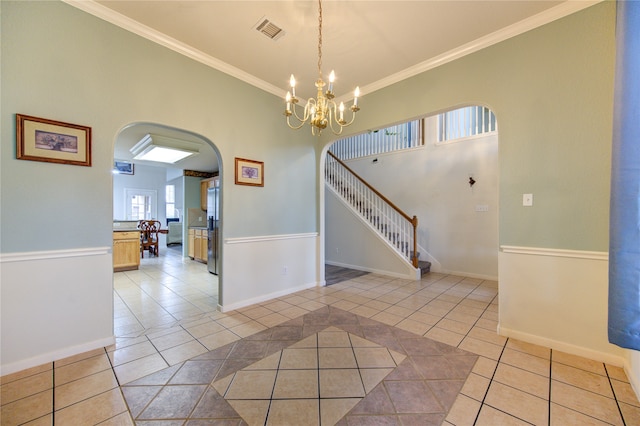 interior space with light tile patterned floors, a chandelier, vaulted ceiling, and ornamental molding