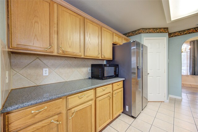 kitchen with stainless steel fridge with ice dispenser, tasteful backsplash, and light tile patterned flooring