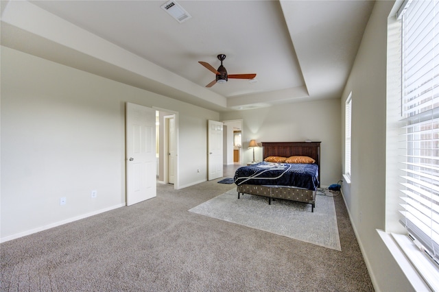 carpeted bedroom with a raised ceiling and ceiling fan