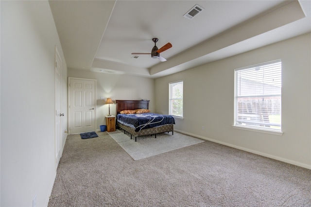 bedroom featuring light carpet, a tray ceiling, and ceiling fan