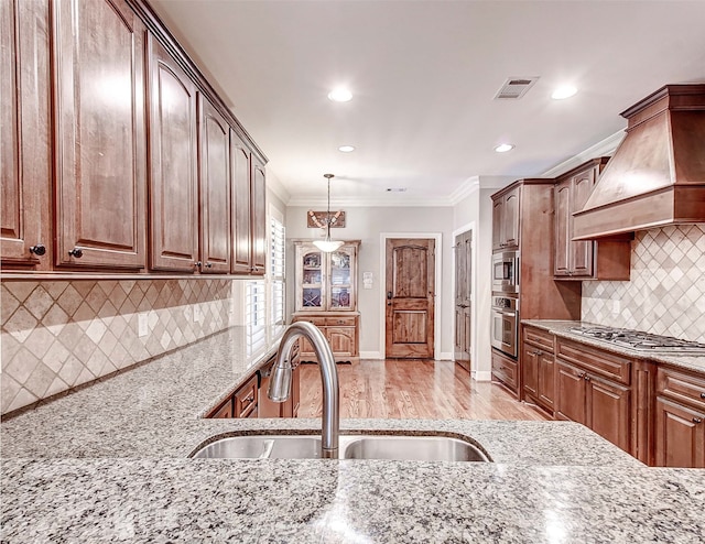 kitchen with premium range hood, crown molding, sink, and light hardwood / wood-style flooring