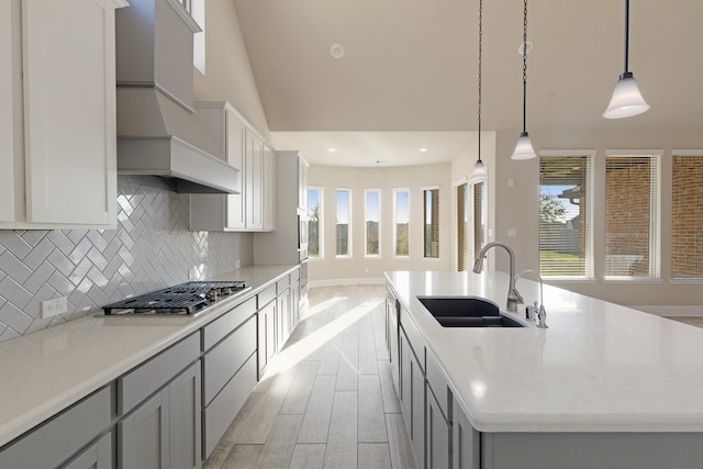 kitchen featuring hanging light fixtures, a kitchen island with sink, a healthy amount of sunlight, and sink