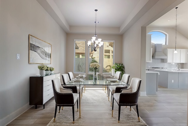 dining room with sink, a chandelier, vaulted ceiling, and light hardwood / wood-style floors