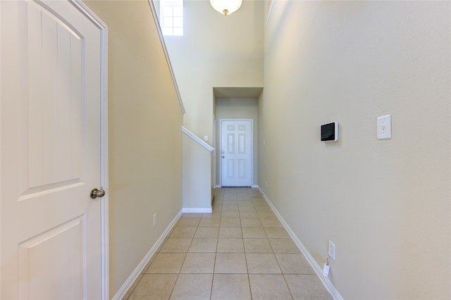 hall featuring a towering ceiling and light tile patterned floors