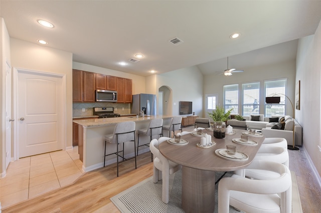 dining area featuring ceiling fan, vaulted ceiling, and light hardwood / wood-style flooring