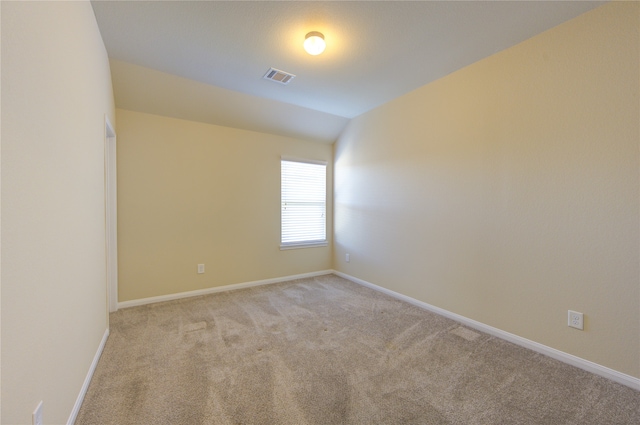 carpeted spare room featuring vaulted ceiling