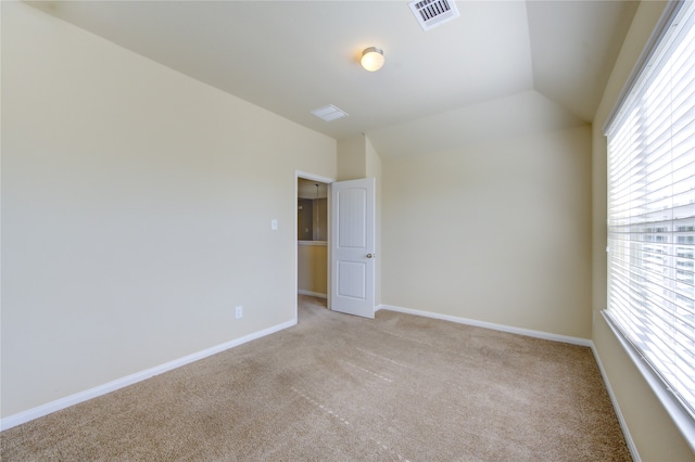 carpeted empty room with lofted ceiling