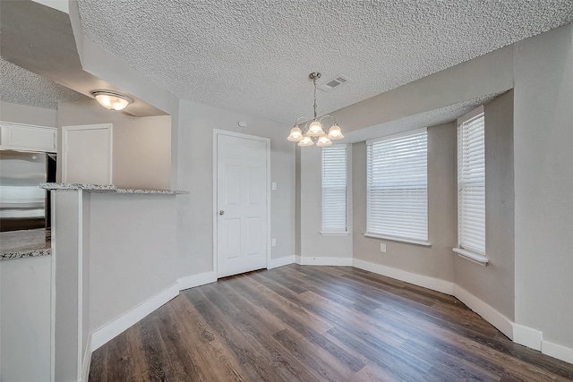 unfurnished dining area with a notable chandelier, dark hardwood / wood-style floors, and a textured ceiling