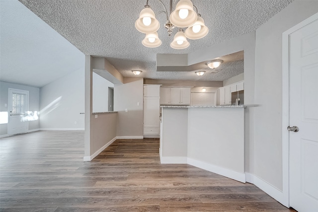 kitchen with hanging light fixtures, dark hardwood / wood-style floors, a textured ceiling, white cabinetry, and stainless steel built in refrigerator