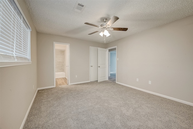 unfurnished bedroom featuring carpet flooring, a textured ceiling, connected bathroom, and ceiling fan