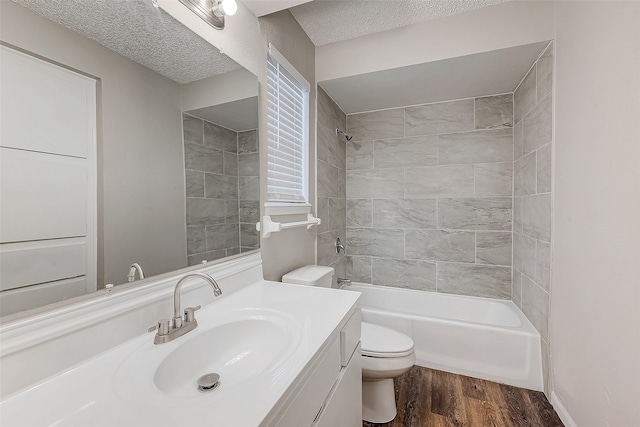 full bathroom with hardwood / wood-style floors, a textured ceiling, toilet, vanity, and tiled shower / bath