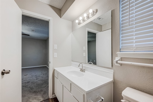 bathroom featuring vanity, a textured ceiling, and toilet